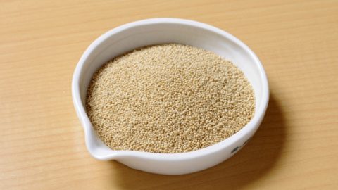 small white bowl of pearl millet on a cutting board