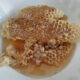 raw honey with intact honeycomb from backyard beehive in white bowl