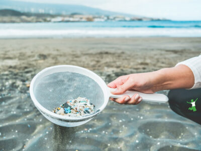 woman with sieve of microplastics contamination at the beach