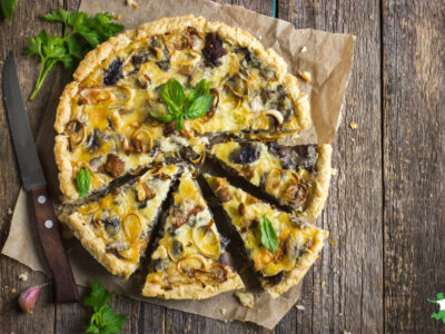 homemade quiche made with leftovers on wooden table with knife