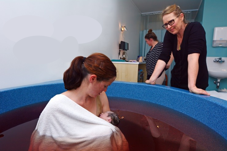 mother nursing newborn in dirty water in birthing pool