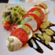 traditional caprese salad on white plate with balsamic drizzle