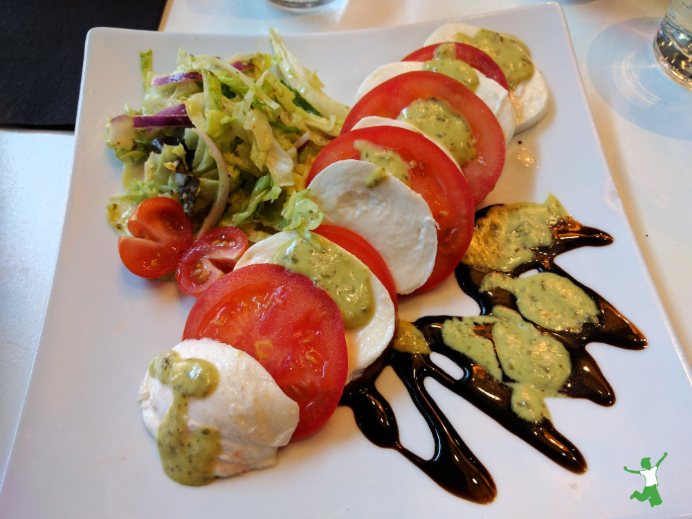 traditional caprese salad on white plate with balsamic drizzle