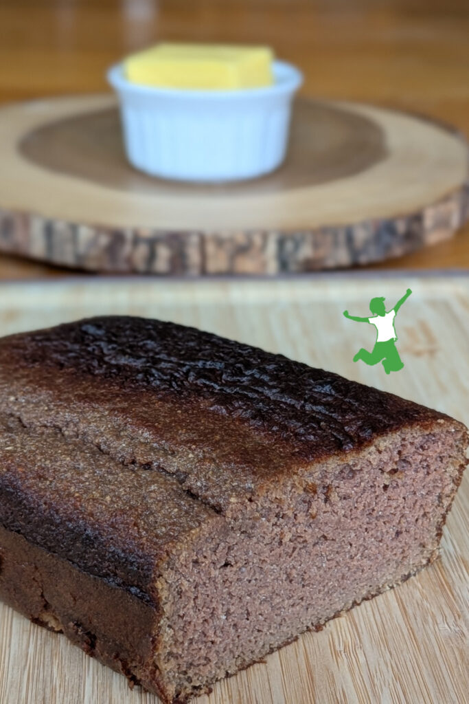 loaf of grain-free date honey pound cake on cutting board with butter