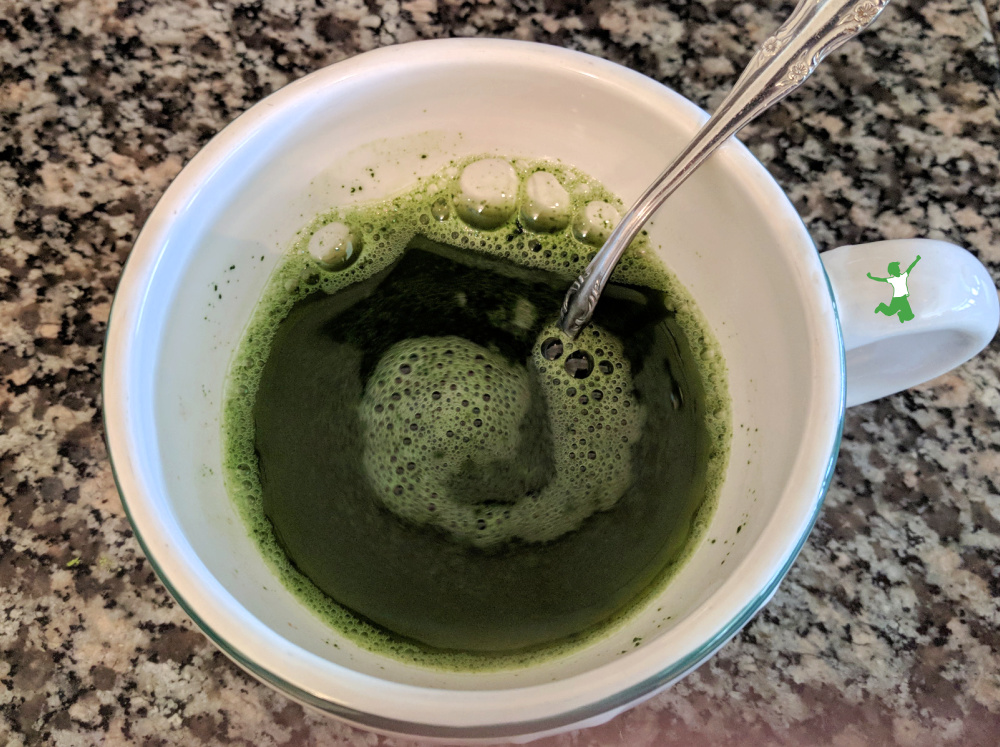 authentic matcha powder in hot water in mug with spoon